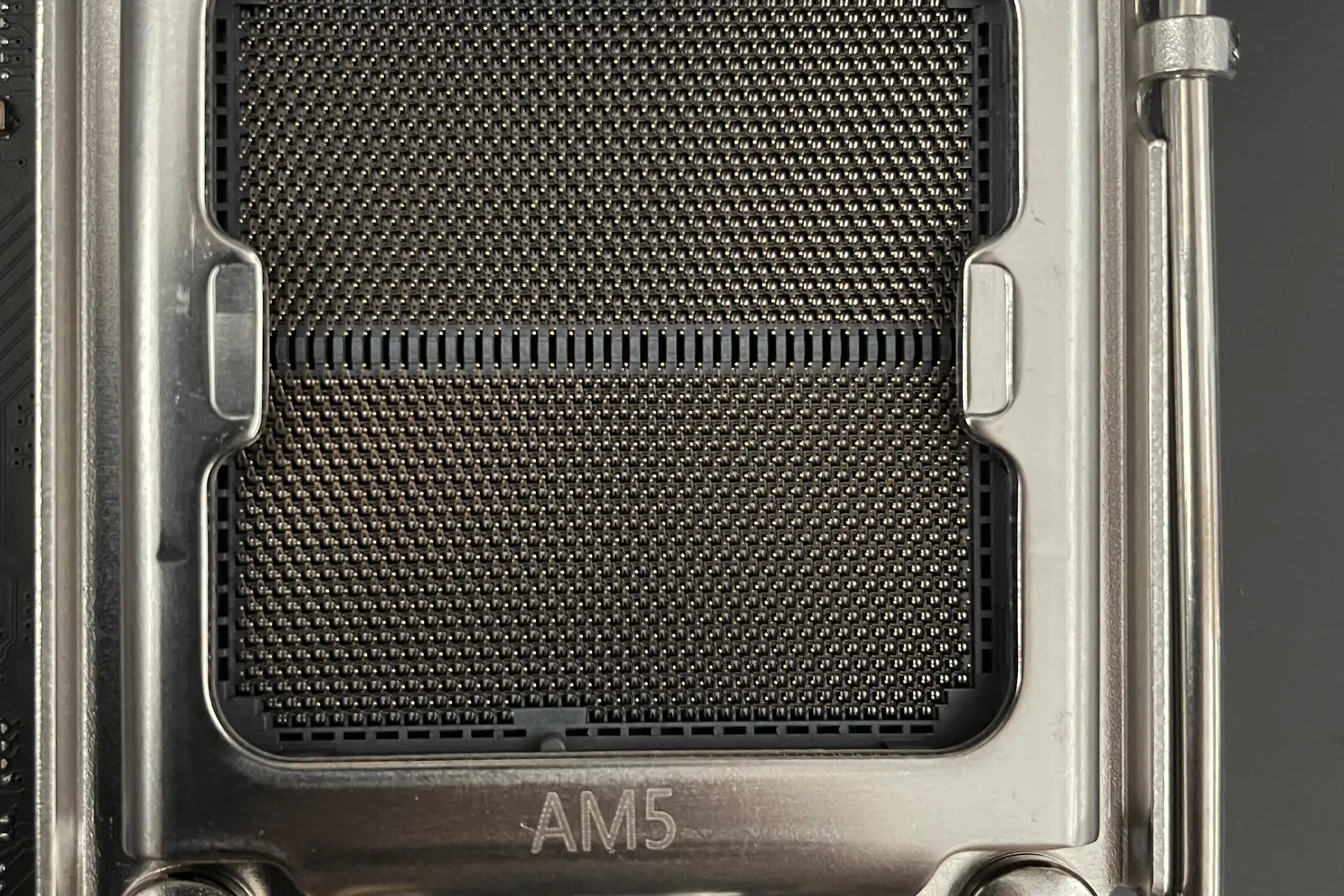 An open AMD Socket AM5 on a motherboard, the retention frame AM5 marking and the dense land grid of the socket in sharp focus