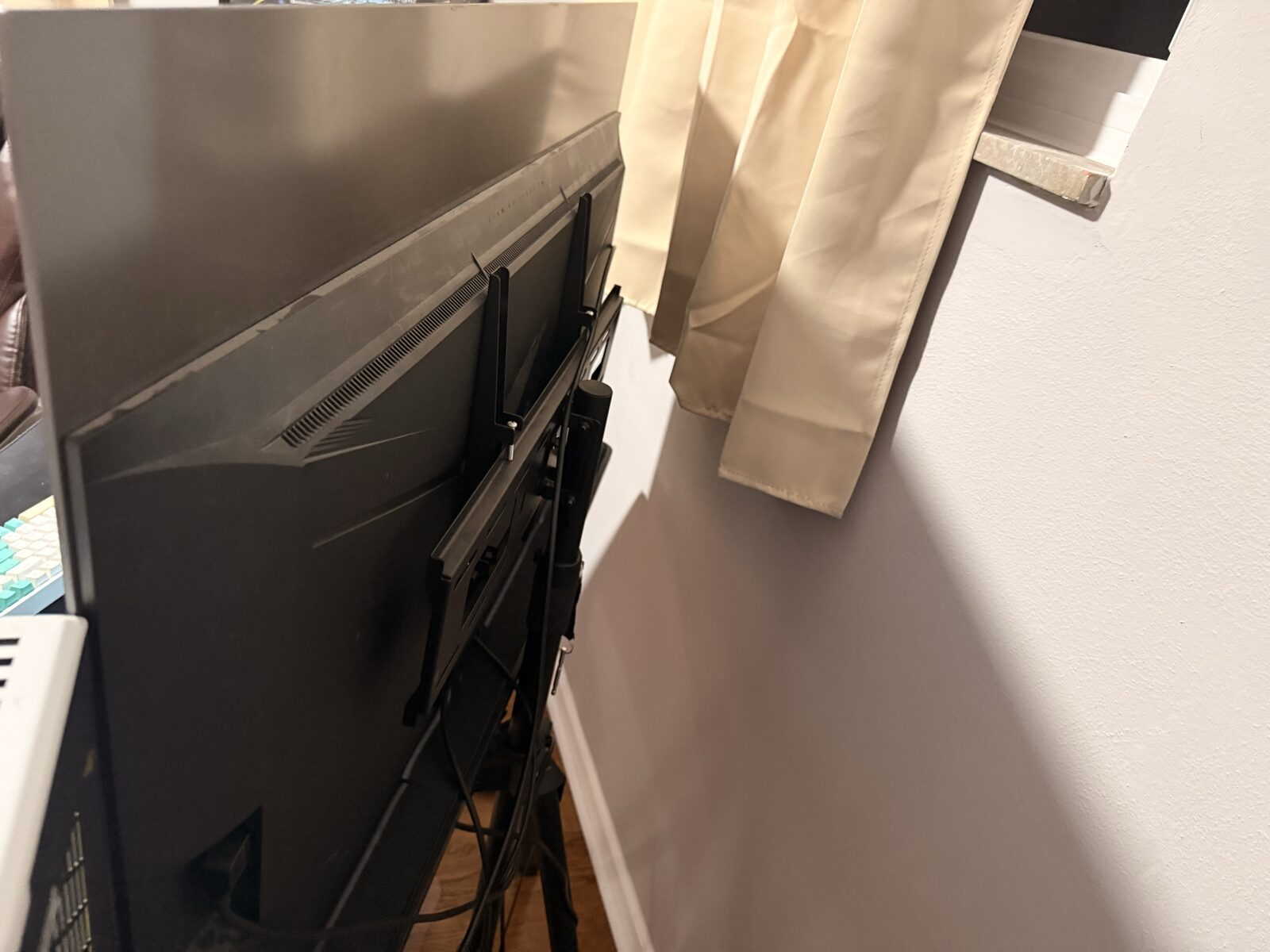 Back of the AORUS FO48U showing the VESA-mount adapter plate and tripod-style stand bracket with cable routing