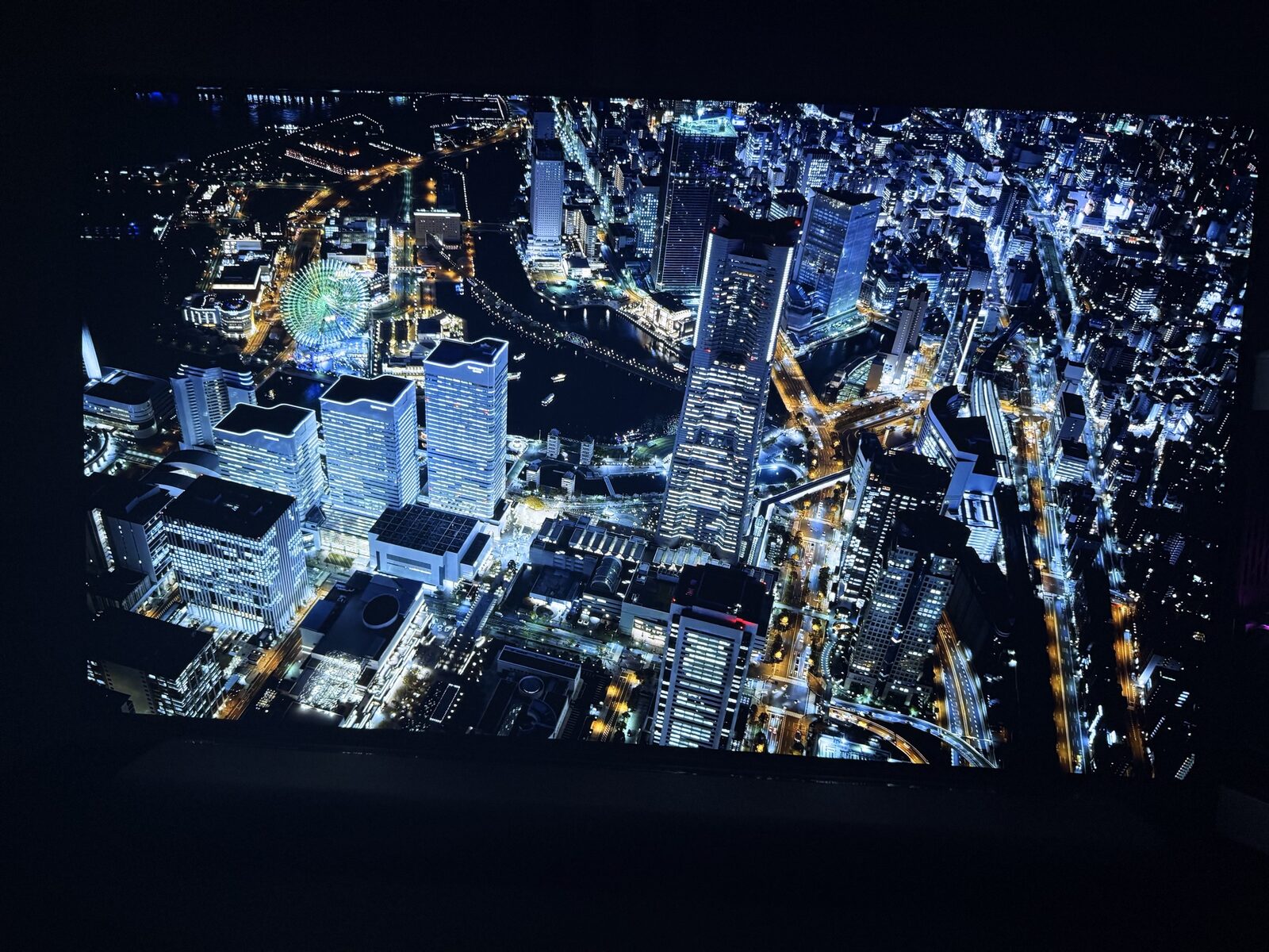 AORUS FO48U showing aerial Yokohama bay night cityscape, OLED contrast between water and city lights, Landmark Tower visible at right