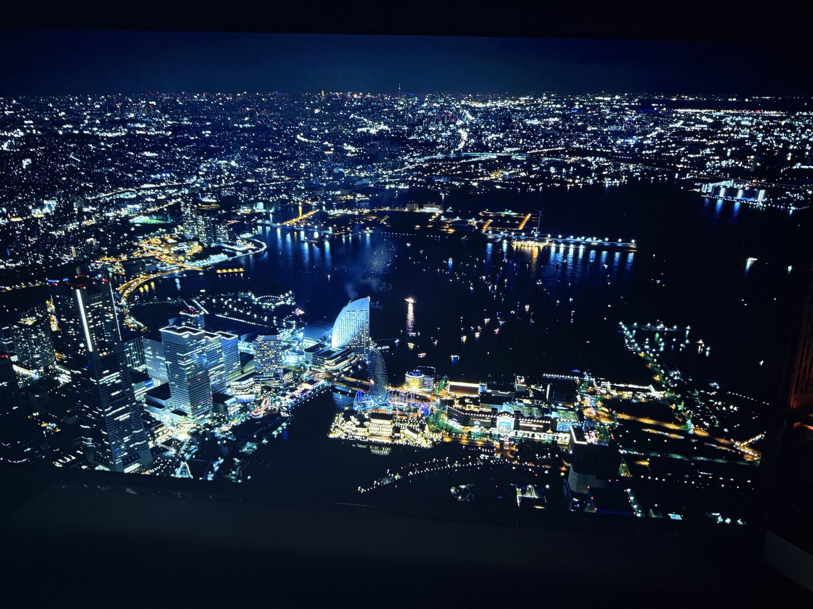 AORUS FO48U displaying Yokohama Marine and Walk venue with dome arena and waterfront at night, mid-tier city detail visible across the 48-inch panel