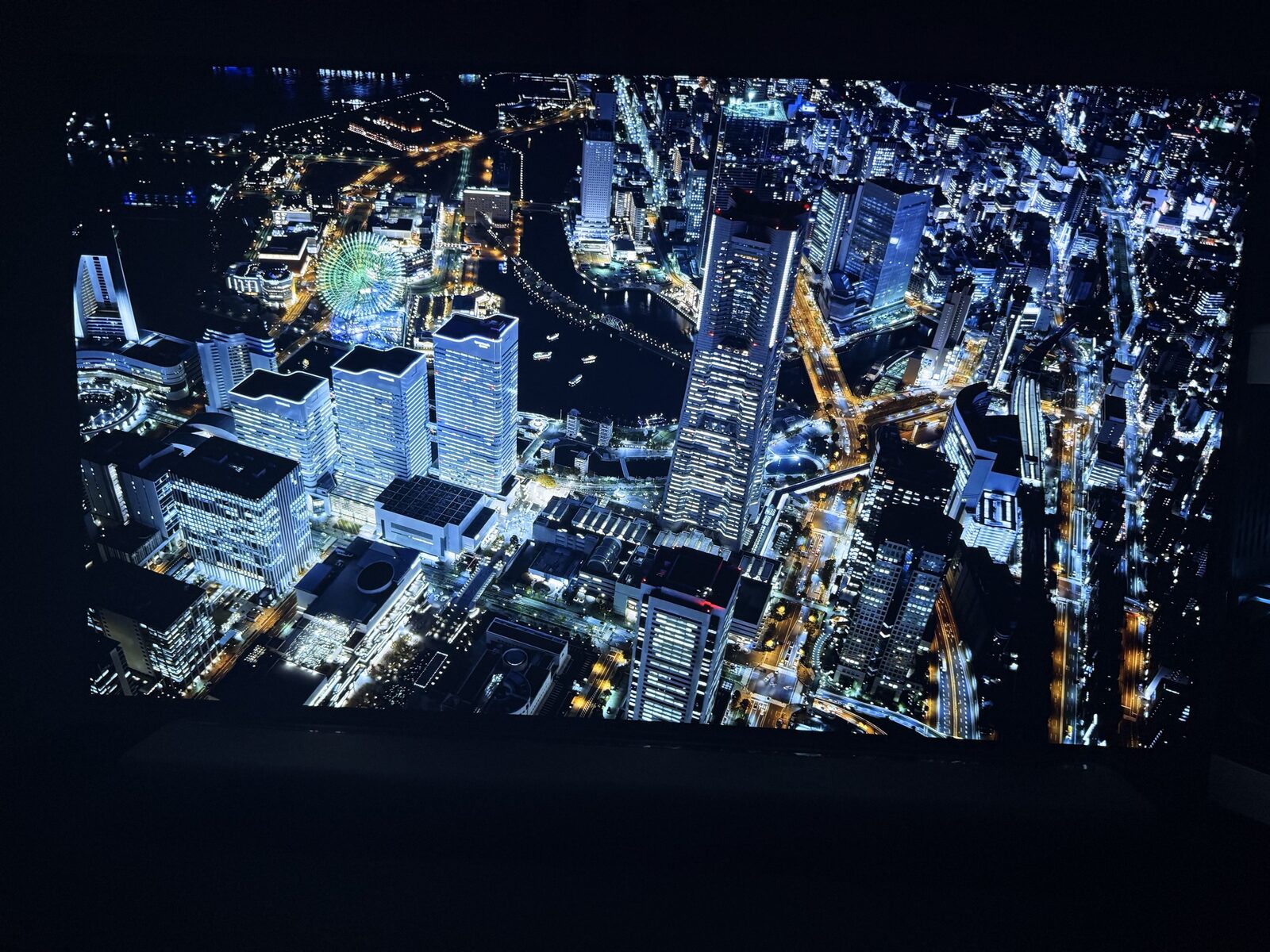 AORUS FO48U showing Yokohama night cityscape close-up with bright building lights against pure OLED black, demonstrating per-pixel black levels