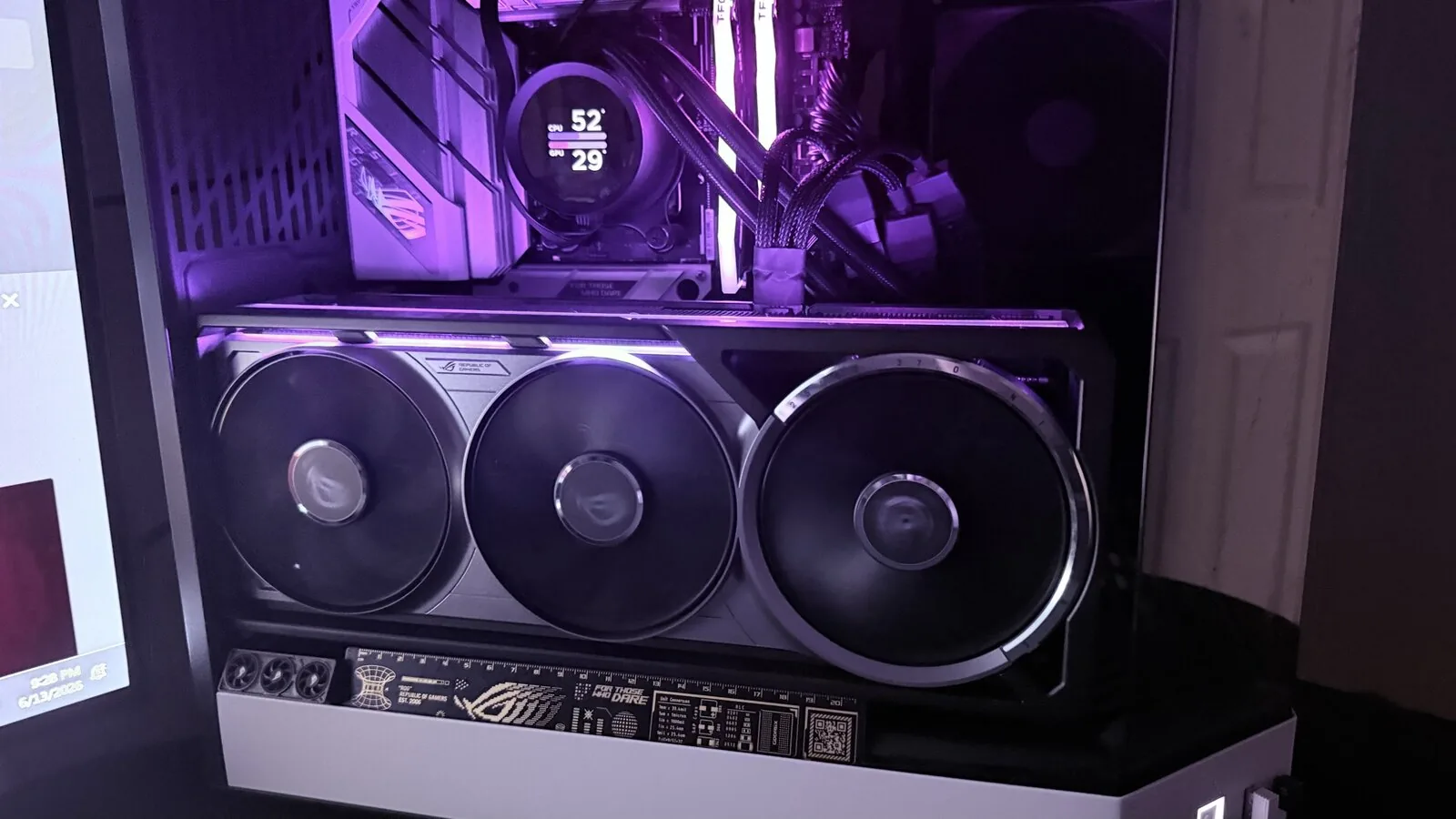 An ASUS ROG Astral RTX 5080 OC installed in a glass-sided case, three fans and lit RGB bar visible, the AIO screen reading 52 and 29 degrees
