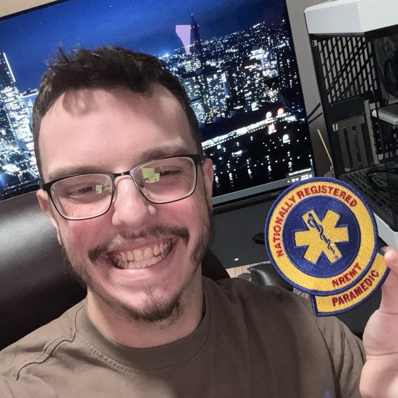 L.K. Wood IV holding an NREMT Paramedic patch in front of his test bench, St. Louis, Missouri