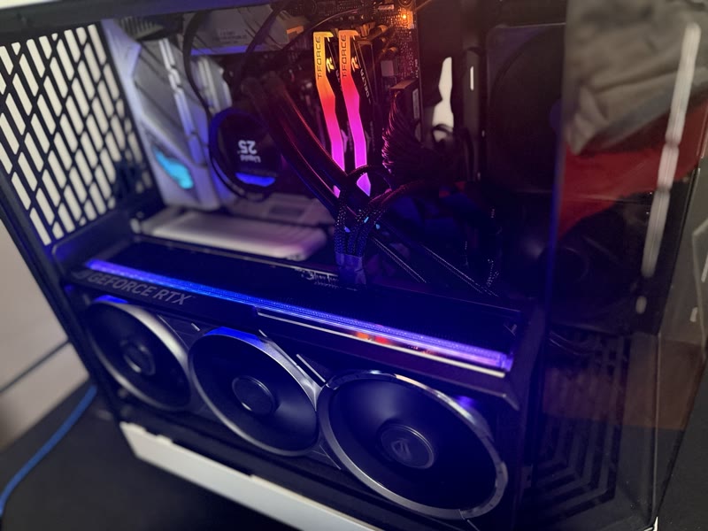 Wider in-case view of the ASUS ROG Astral RTX 5080 OC with GeForce RTX badge lit blue, T-Force RGB DDR5 with an inked signature on the heatspreader, NZXT Kraken AIO above