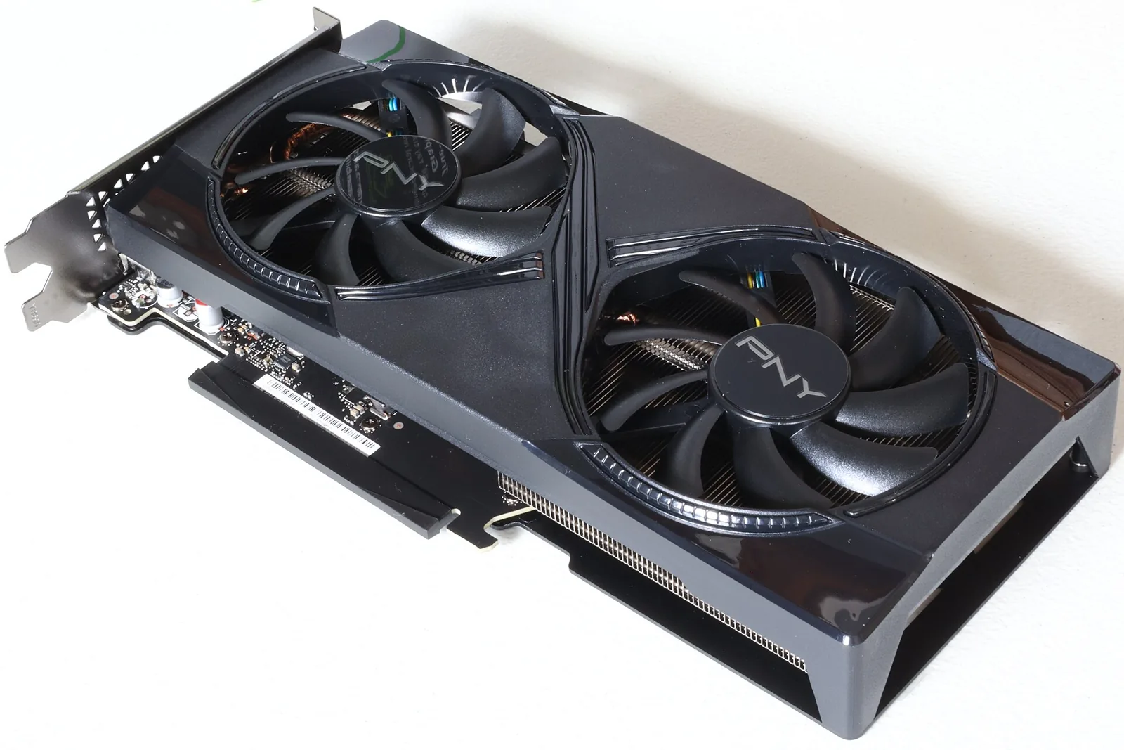 A PNY GeForce RTX 5060 Ti 16GB dual-fan graphics card lying face up on a white surface, seen from a three-quarter angle