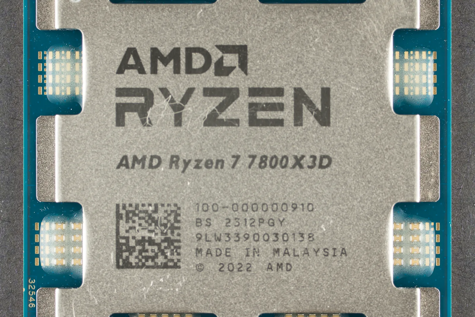 Close-up of an AMD Ryzen 7 7800X3D processor, its heat spreader stamped with the model name and the part number 100-000000910